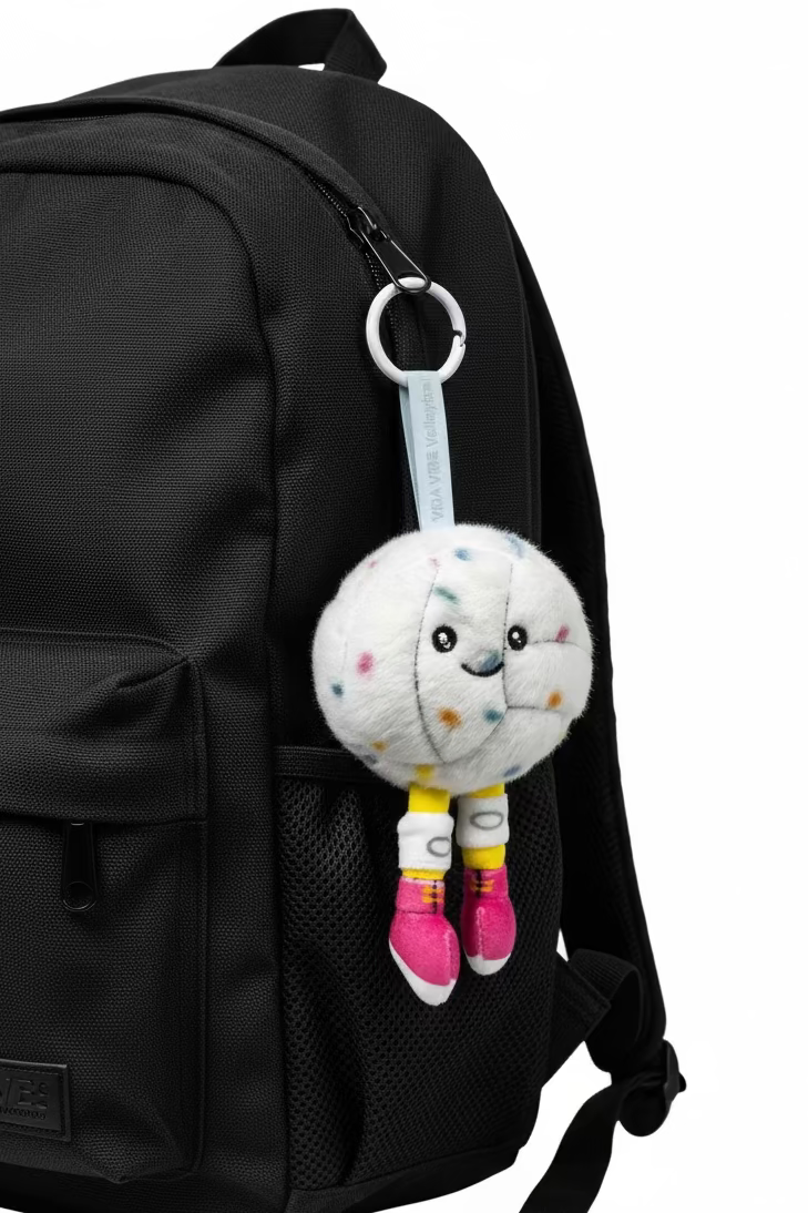 Plush volleyball toy with a face and colorful accents on a gray background
